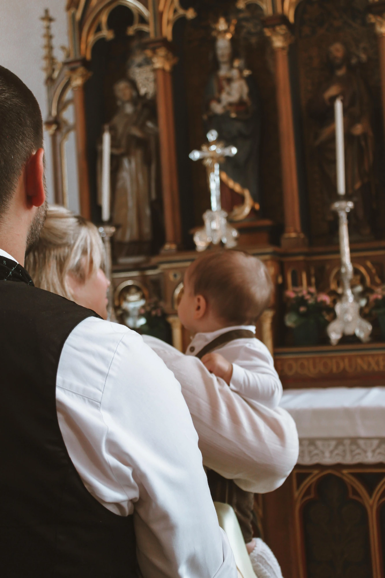 Taufpaten mit brennender Taufkerze in der Kirche